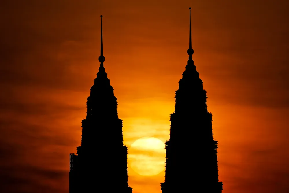 The sun rises behind Petronas Twin Towers - Petronas' headquarters - in Kuala Lumpur, Malaysia.