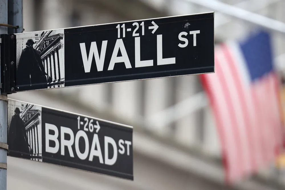 A Wall Street sign hangs in front of a U.S. Flag outside the New York Stock Exchange.