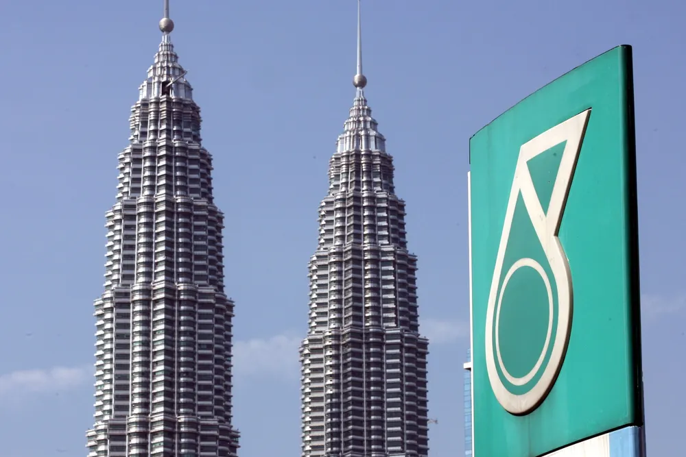 The Petronas twin towers is seen behind the company's corporate logo in downtown Kuala Lumpur