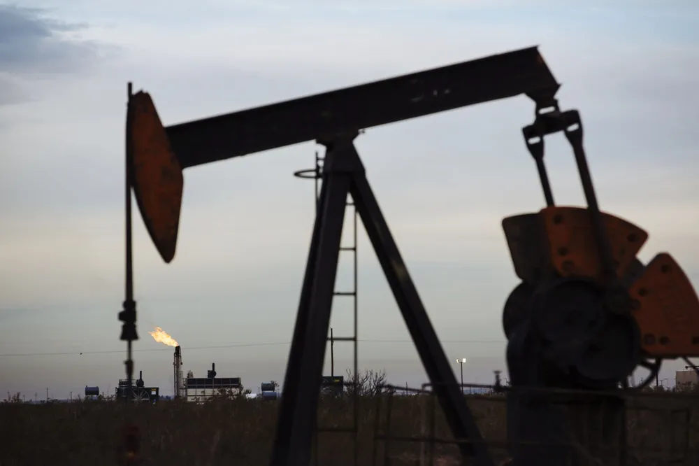 A gas flare burns past a pump jack in the Permian Basin area of Loving County, Texas, U.S., on Monday, Dec. 17, 2018. Once the shining star of the oil business, gasoline has turned into such a drag on profits that U.S. refiners could be forced to slow production in response. Photographer: Angus Mordant/Bloomberg