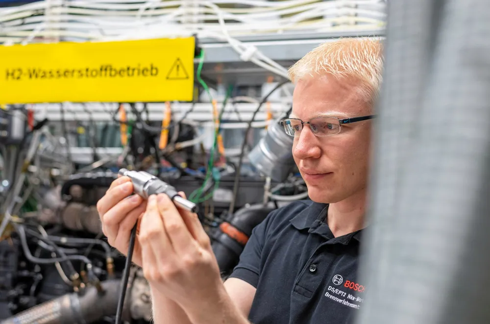 A Bosch worker holding a hydrogen fuel injector for an H2 engine.