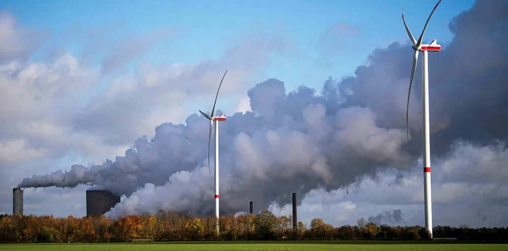 Wind turbines turn as pollution billows from RWE's coal-fired Niederaussem plant in Germany