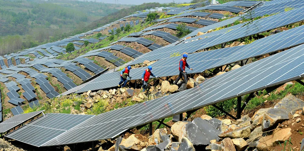 Workers check PV modules on a hillside in a village in Chuzhou, in eastern Anhui Province, China