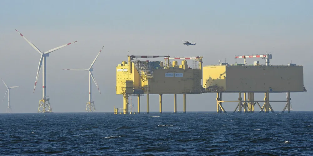 A wind turbine is pictured next to an electrical offshore substation operated by European electricity transmission system operator (TSO) TenneT near the German offshore wind farm "Amrum Bank West".