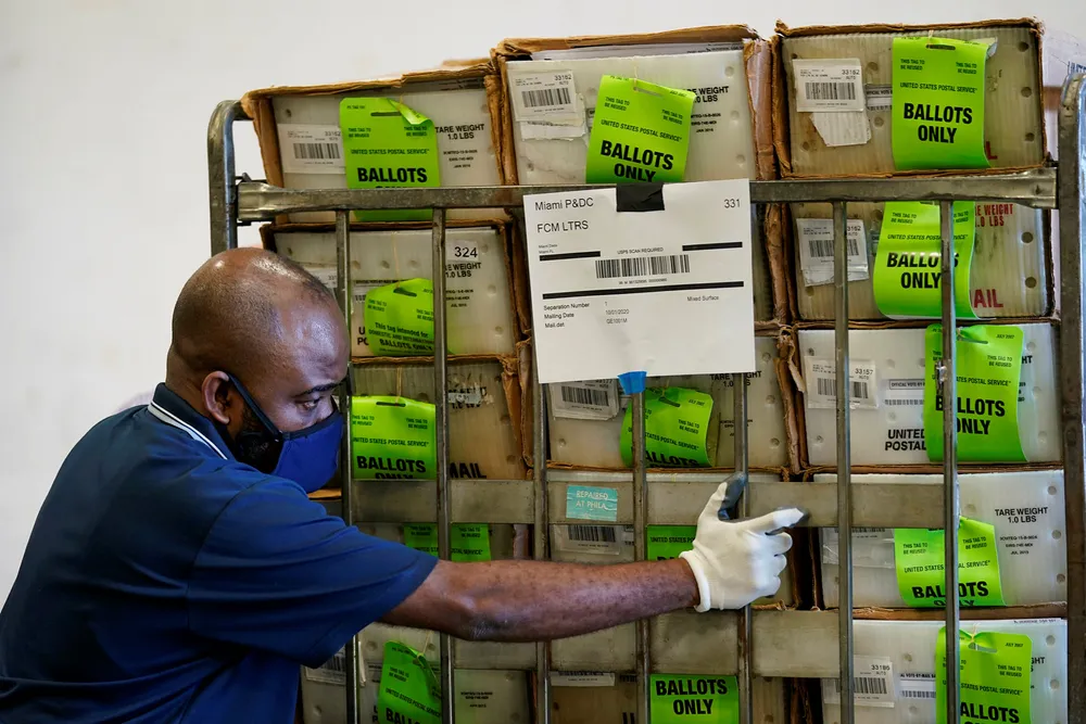 En valgfunksjonær i Miami laster poststemmesedler i en bil. Sedlene skal fraktes til velgere som har søkt om å stemme i det kommende presidentvalget via posten.