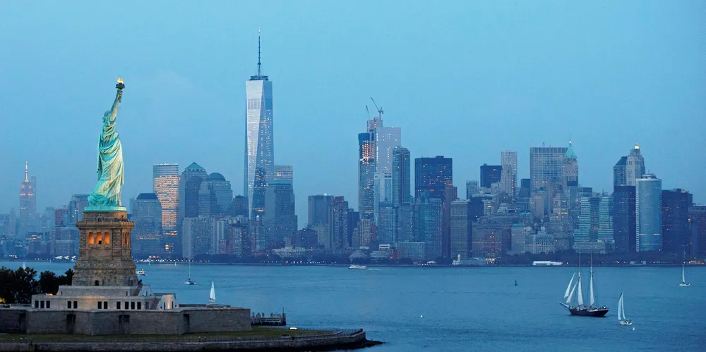 The Statue of Liberty stands in the foreground as Lower Manhattan is viewed at dusk.
