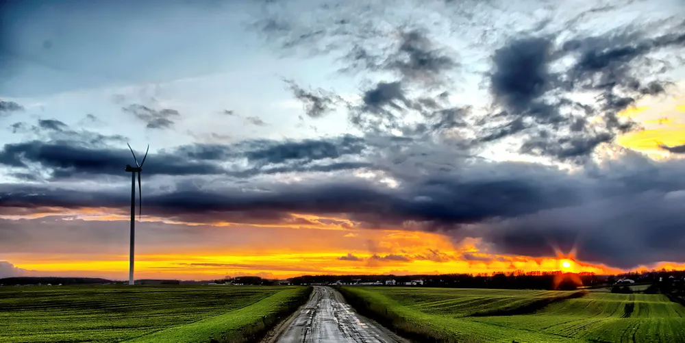 A road between fields and a wind turbine in Poland