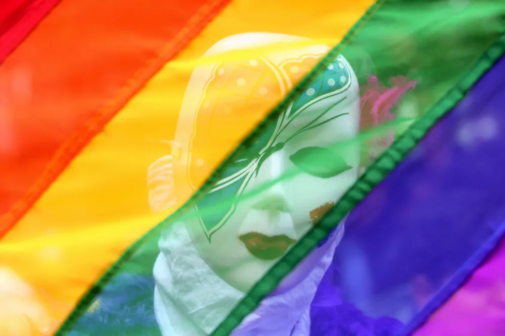 Flag day: a participant stands behind a rainbow flag during a gay pride parade