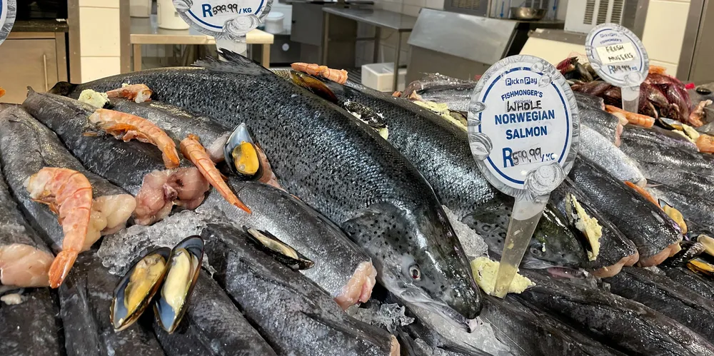 Norsk laks i sør-afrikansk supermarked, hos supermarkedkjeden Pick n’save midt i Cape Town. 100 rand tilsvarer ca. 58 norske kroner. Den ansatte sier at de selger laksen for det meste i ferdige porsjonsstykker, det vil si at et porsjonsstykke er dyrere enn en hel fisk.