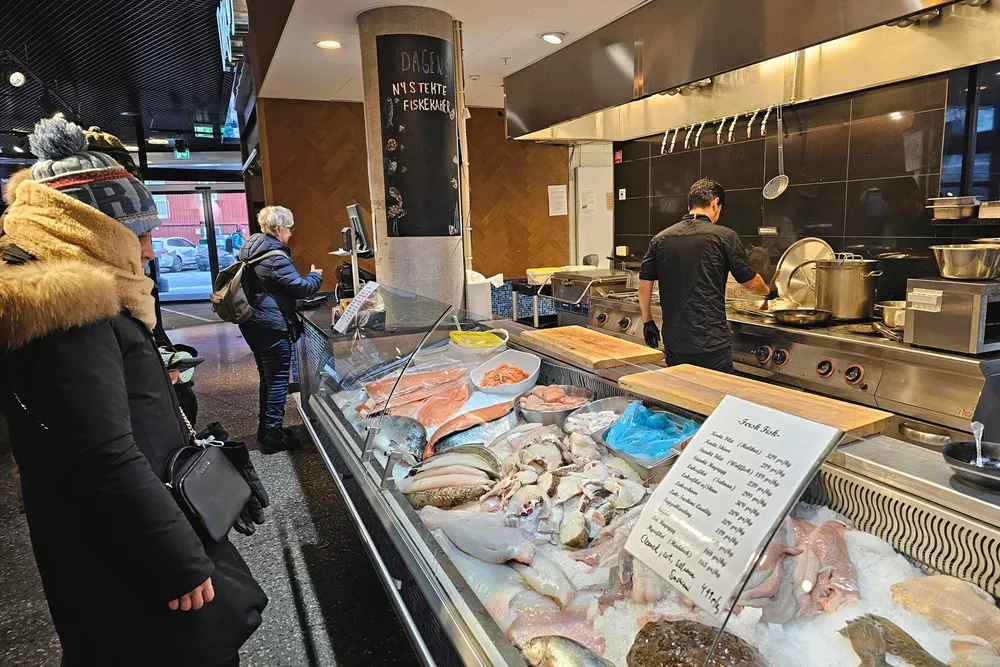 Sjømatdisken til fiskebutikken Dragøy på Kysten hus i Tromsø. Her er det turister som flokker seg rundt disken rett som det er.