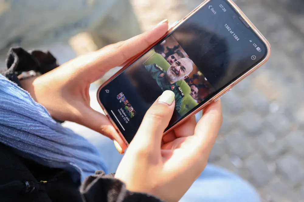 A woman looks at a photo of the leader of Iran's Islamic Revolutionary Guard Corps, Major Hossein Salami, as she follows the news of Israel's strikes against Iran.