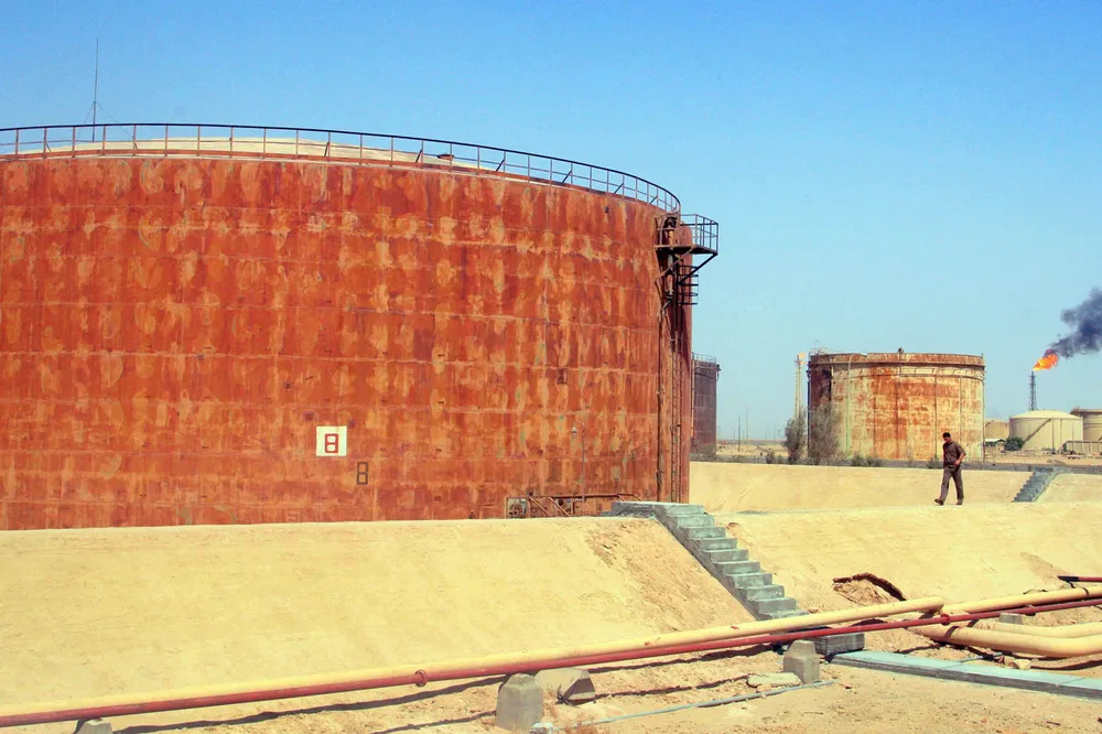 The oilfields surrounding the southern city of Basra have become the centre of speculation: here an Iraqi walks past oil reservoirs at the Iraqi Pipelines Company in the city