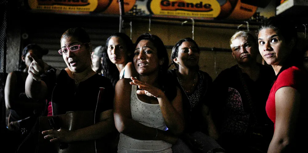 Workers wait inside a dark mall during a power outage in Maracaibo, Venezuela.