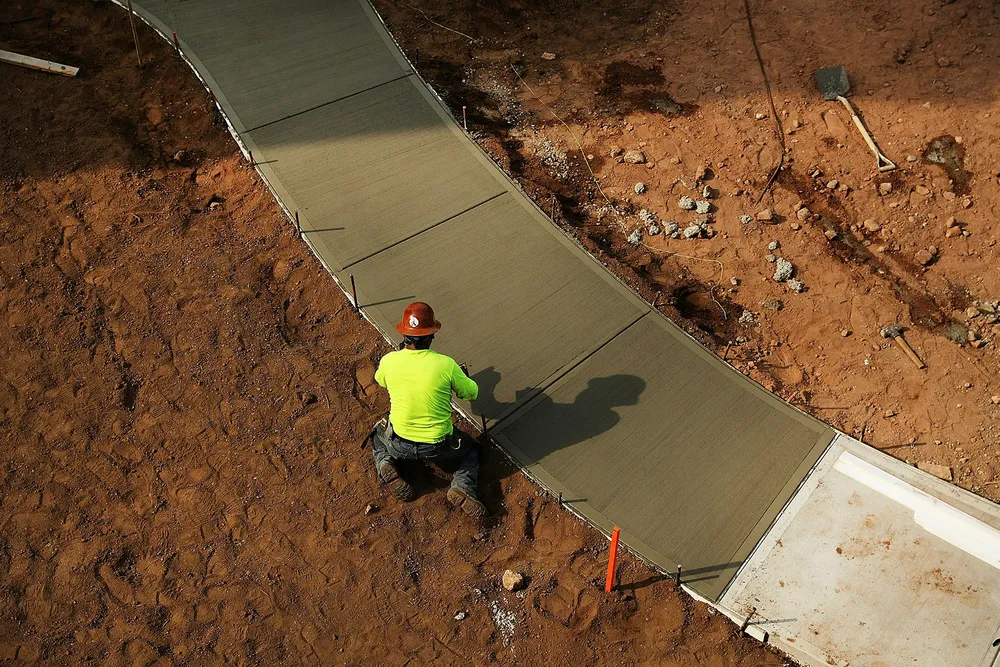 En arbeider er i ferd med å legge fortau i et nytt boligfelt nær byen New Haven i delstaten Connecticut i USA tidligere denne uken. Foto: SPENCER PLATT / AFP / NTB Scanpix