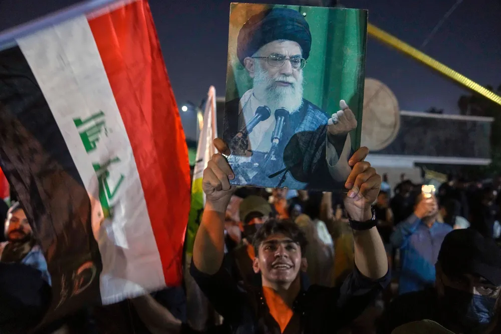 A protest holds a portrait of Iran's Supreme Leader Ayatollah Ali Khamenei during a protest against Israeli attacks on multiple cities across Iran, at a bridge leading to the fortified Green Zone where the U.S. embassy is located in Baghdad, Iraq, Saturday, June 14, 2025. (AP Photo/Hadi Mizban)