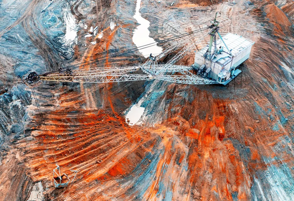 A large walking excavator works in a quarry for the extraction of rare metals. Drone view. Industrial landscape. . Rare earth.