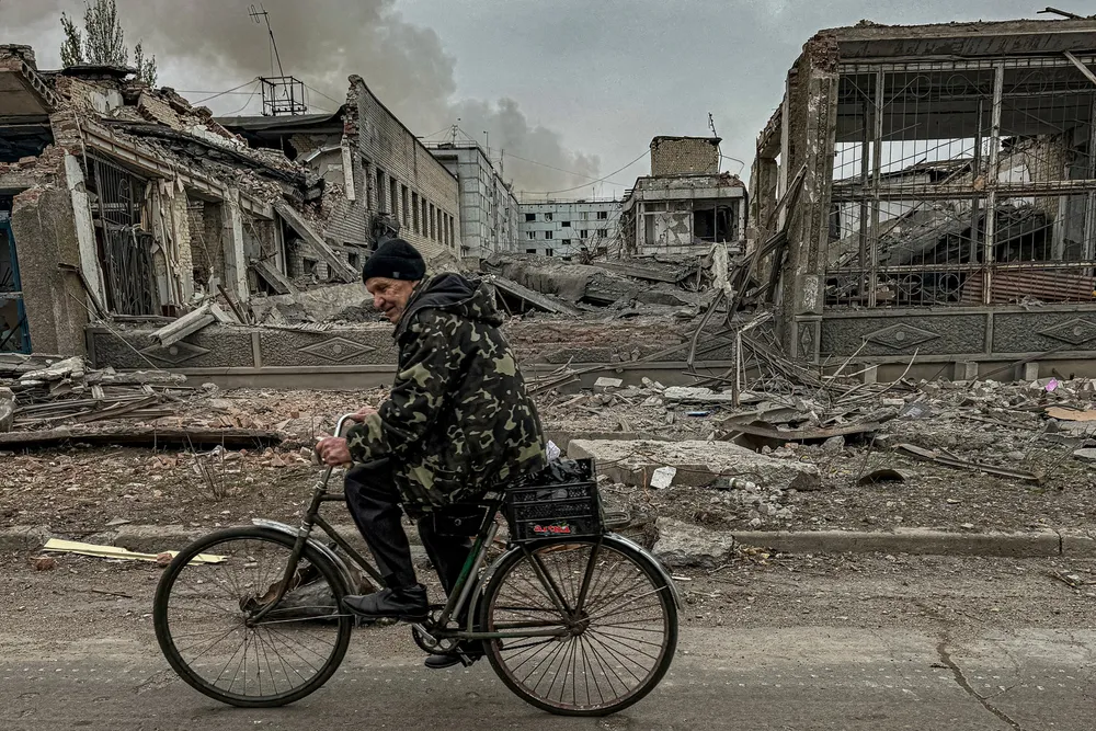 En mann sykler gjennom utbombede områder av byen Kurakhove i Donetsk-regionen. Russerne er på frammarsj. Mange innbyggere har valgt å evakuere, mens andre biter seg fast.