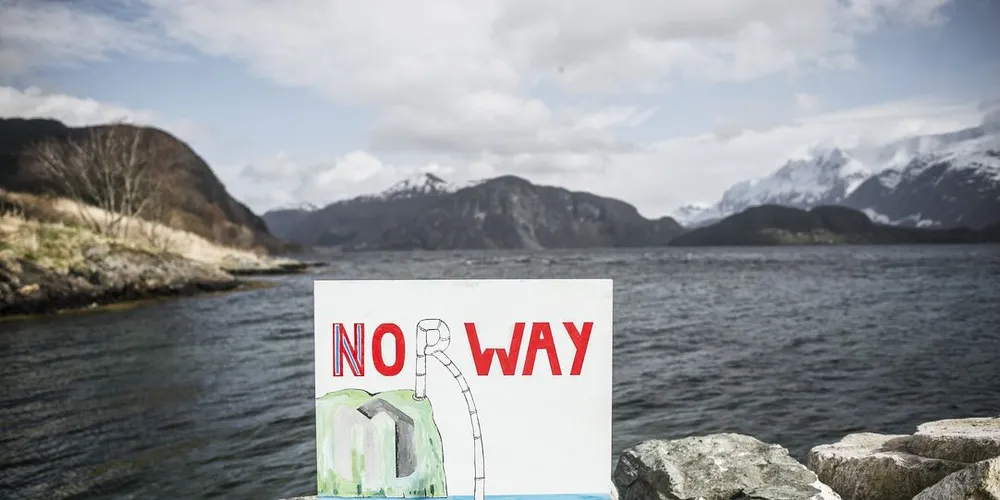 Det omstridte Engebøfjellet på venstre side av bildet. Sjødeponiet kommer rett ut i fjorden bak plakaten. Regjeringa sier ja til Nordic Mining sine planer om rutilutvinning i Engebøfjellet i Naustdal. Nå kan selskapet bli solgt. Luca Kleve-Ruud