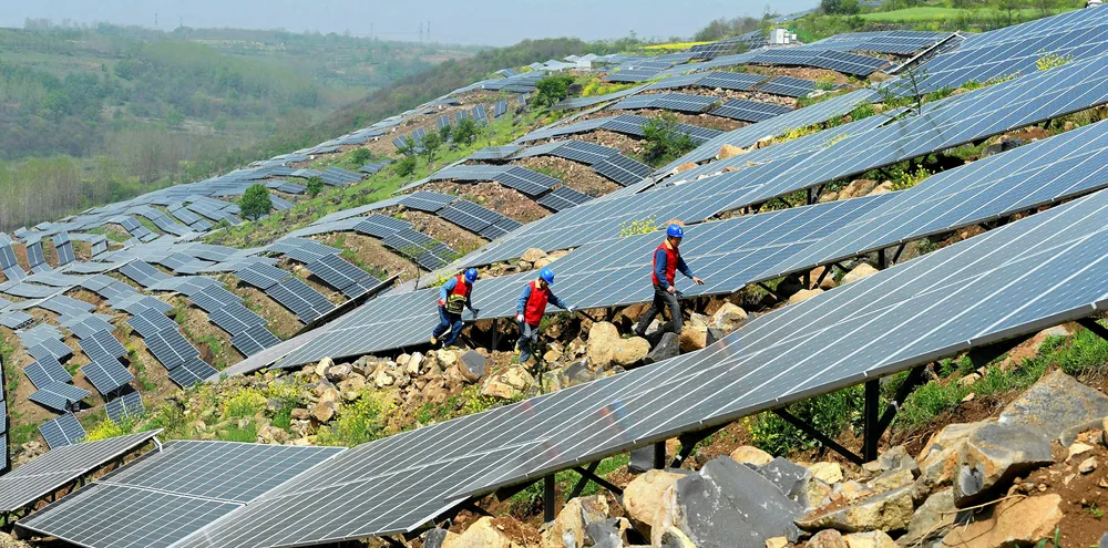 Chinese workers check solar photovoltaic modules on a hillside in a village in Chuzhou, in eastern China's Anhui province