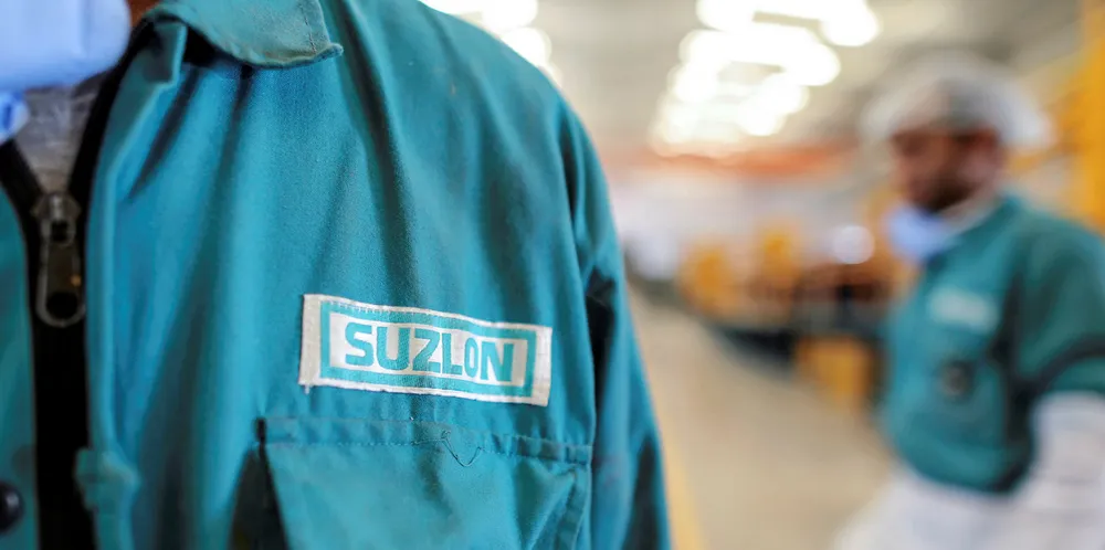 The Suzlon Energy Ltd. logo is displayed on an employee's uniform at the company's rotor blade manufacturing plant in Bhuj, India.