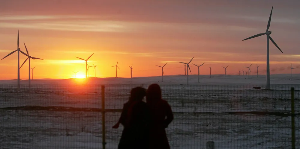 Two tourists view the Huitengxile Wind Farm at sunset January 28, 2007 in Wulanchabu League of Inner Mongolia Autonomous Region, China.