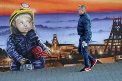 A man walks past a mural outside the corporate headquarters of the JSW mining company on November 30, 2018 in Jastrzebie Zdroj, Poland. JSW operates mines including the KWK Pniowek mine at nearby Pawlowice, Poland's largest coal mine.